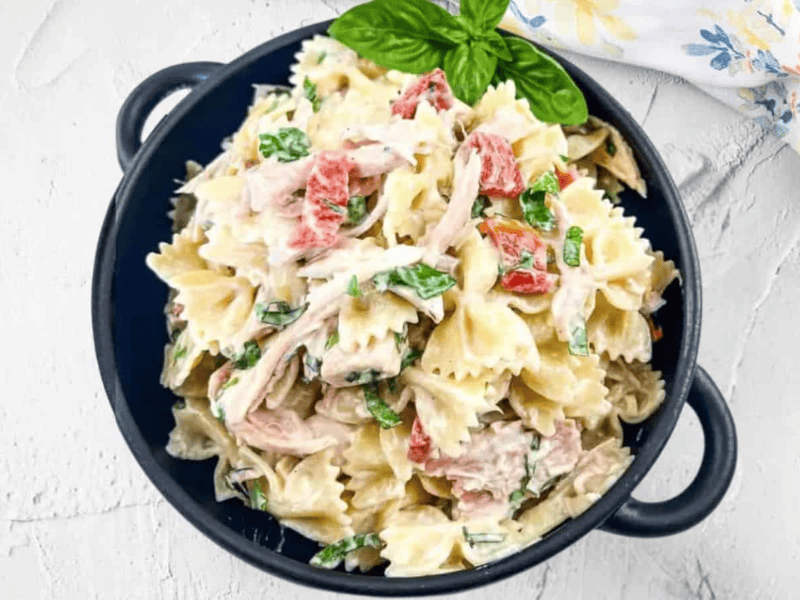 A black bowl filled with rotisserie chicken pasta salad.