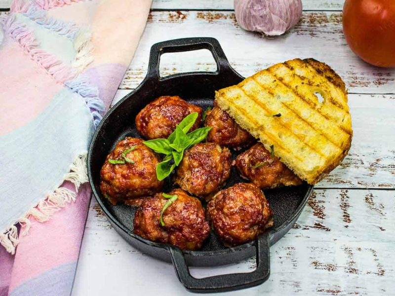 Smoked meatballs in a dish with grilled bread.