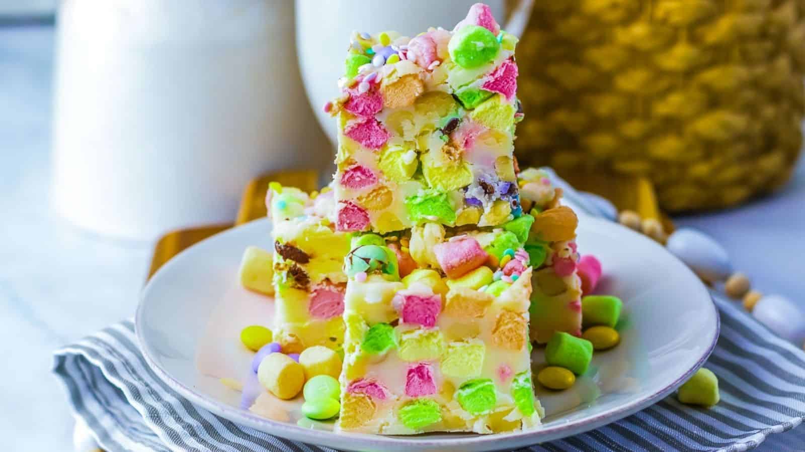 A plate of colorful marshmallow bars stacked on a striped cloth.