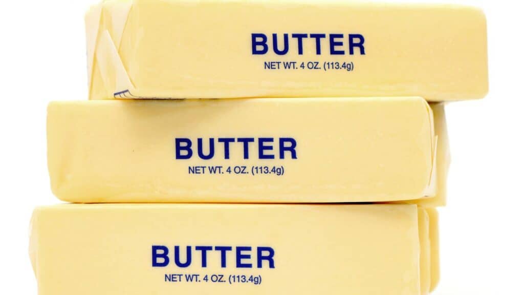 Four sticks of butter stacked, each labeled "BUTTER NET WT. 4 OZ. (113.4g)" on the paper wrapping.
