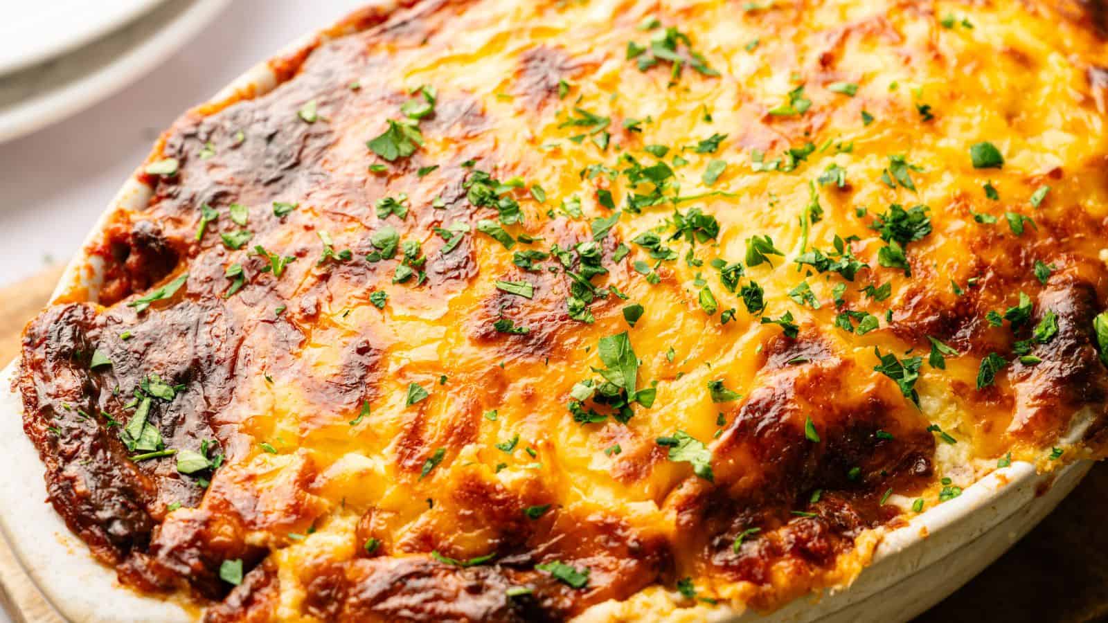 A baked casserole topped with melted, golden-brown cheese and sprinkled with chopped fresh parsley.