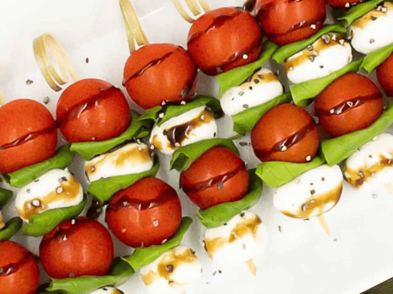 Caprese skewers on a serving dish with balsamic glaze drizzled over.