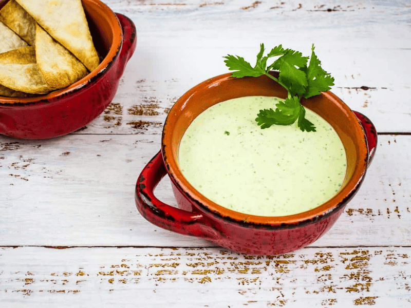 Creamy Jalapeno Dip in a bowl with chip nearby.