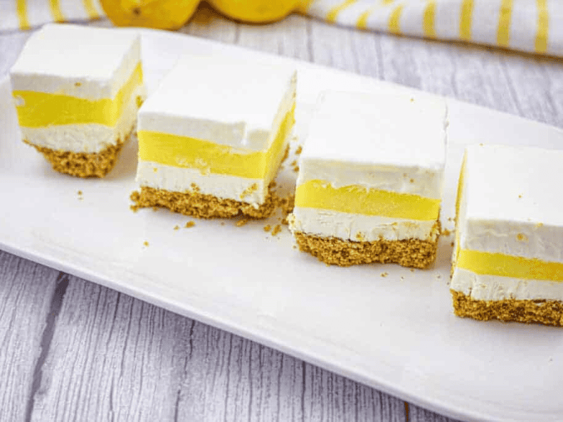 Four pieces of lemon lush on a white plate.