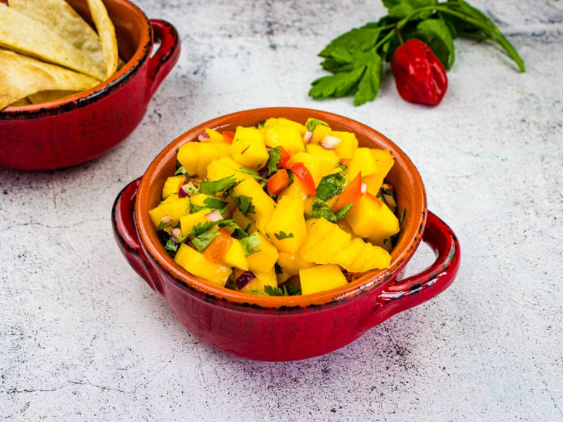 Mango Salsa in a bowl with chips nearby.