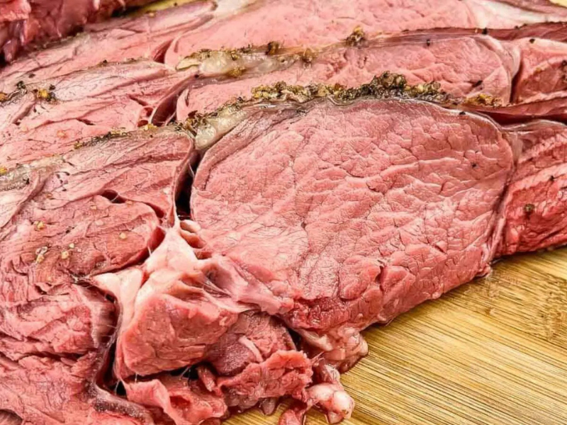 Sliced smoked ribeye beef on a cutting board.