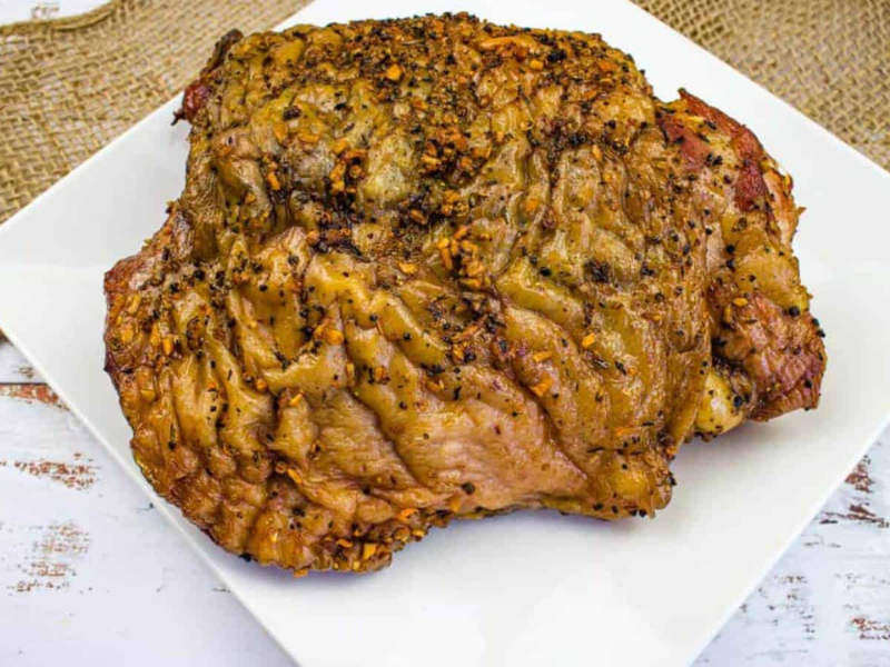 Smoked turkey thigh on a white plate.