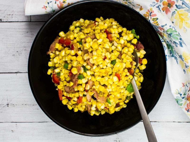 Texas Corn Succotash in a black bowl with spoon.
