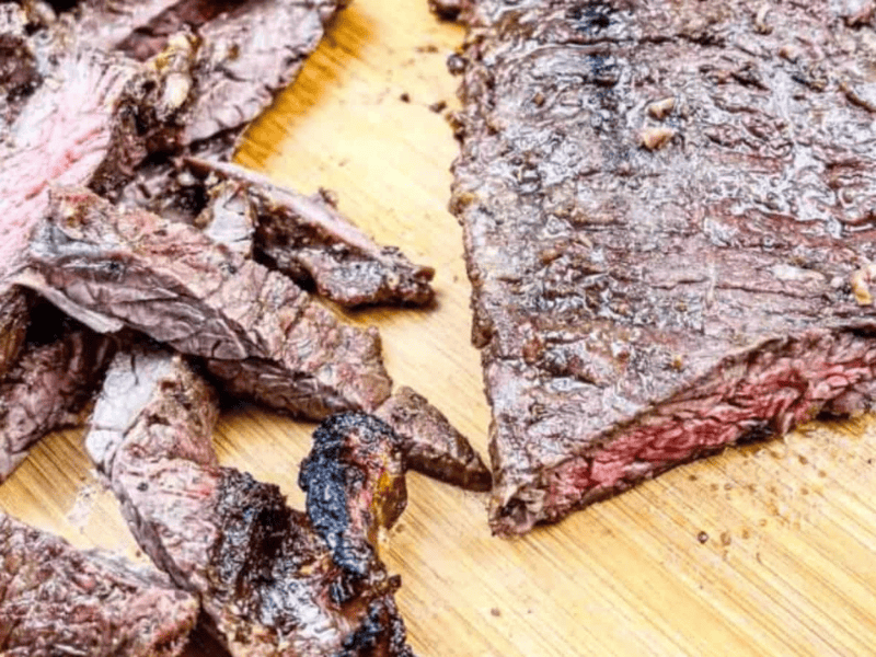 A sliced and grilled Carne asada on a wooden cutting board.