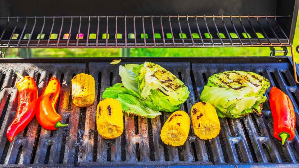 Assorted vegetables, including peppers, corn on the cob, and lettuce, are grilling on an outdoor barbecue grill&mdash;a perfect option for those enjoying flexitarian eating.