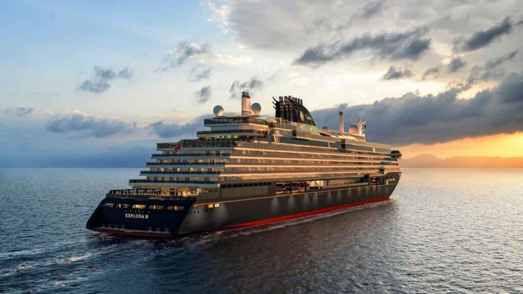 A large modern cruise ship sails on calm water at sunset under a partly cloudy sky.