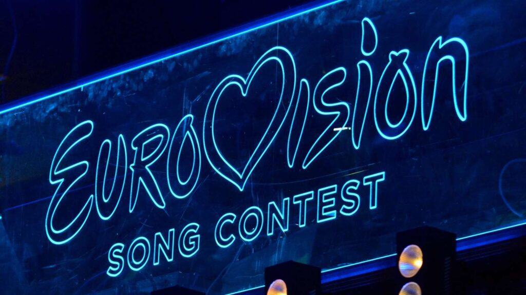 Neon blue sign displays the words "Eurovision Song Contest" with a heart shape replacing the "v" in "Eurovision.