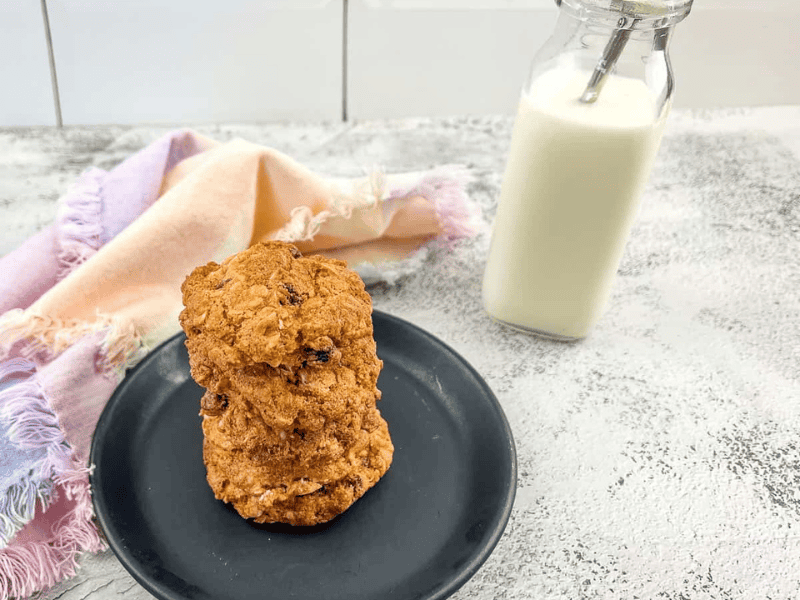 Oatmeal raisin cookies on a plate next to a glass of milk.