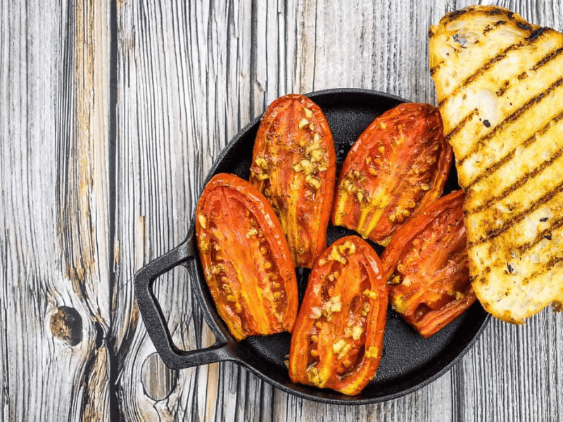 Smoked tomatoes in a dish with grilled bread.