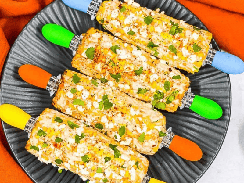Corn on the cob on a black plate.