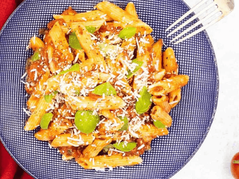 A plate of pasta with tomatoes and parmesan cheese.