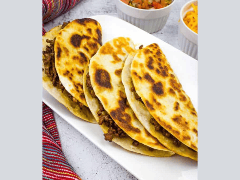 Three Tacos Dorados on a rectangular plate.