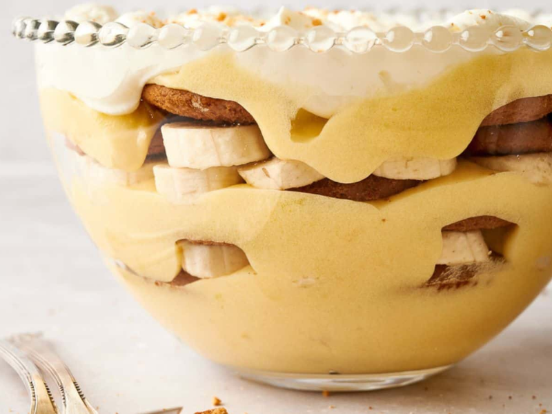 Banana pudding in a bowl with whipped cream and bananas.