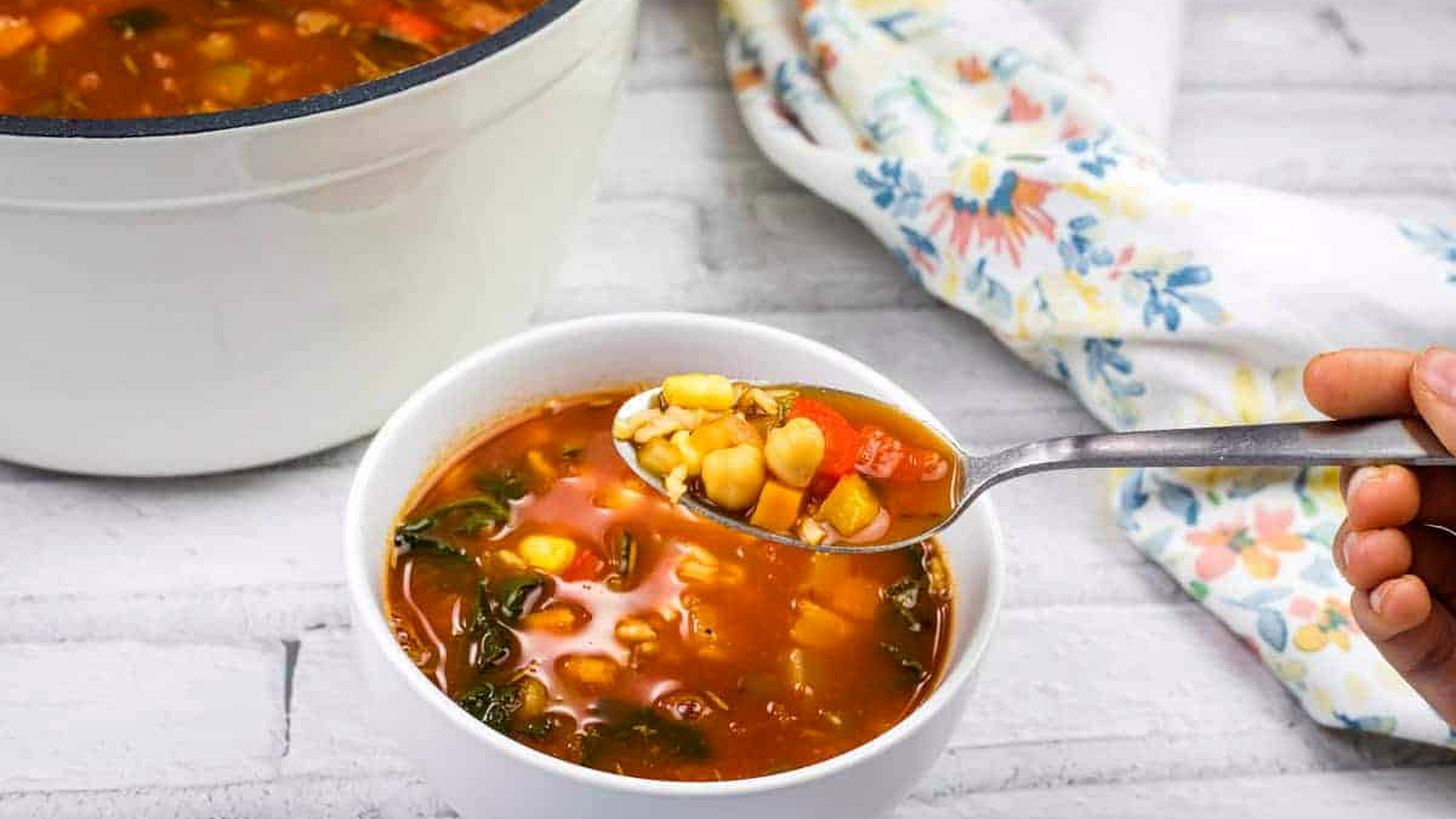 A bowl of Panera Bread&rsquo;s 10 Vegetable soup with beans and greens on a white surface.