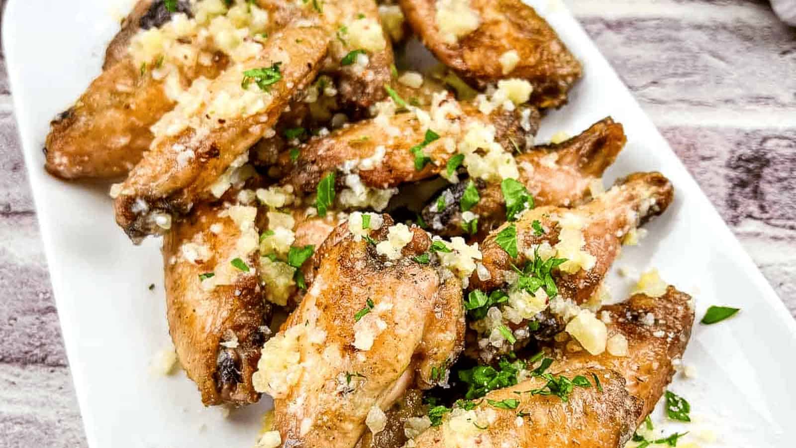 Chicken wings with garlic and Parmesan on a white plate.