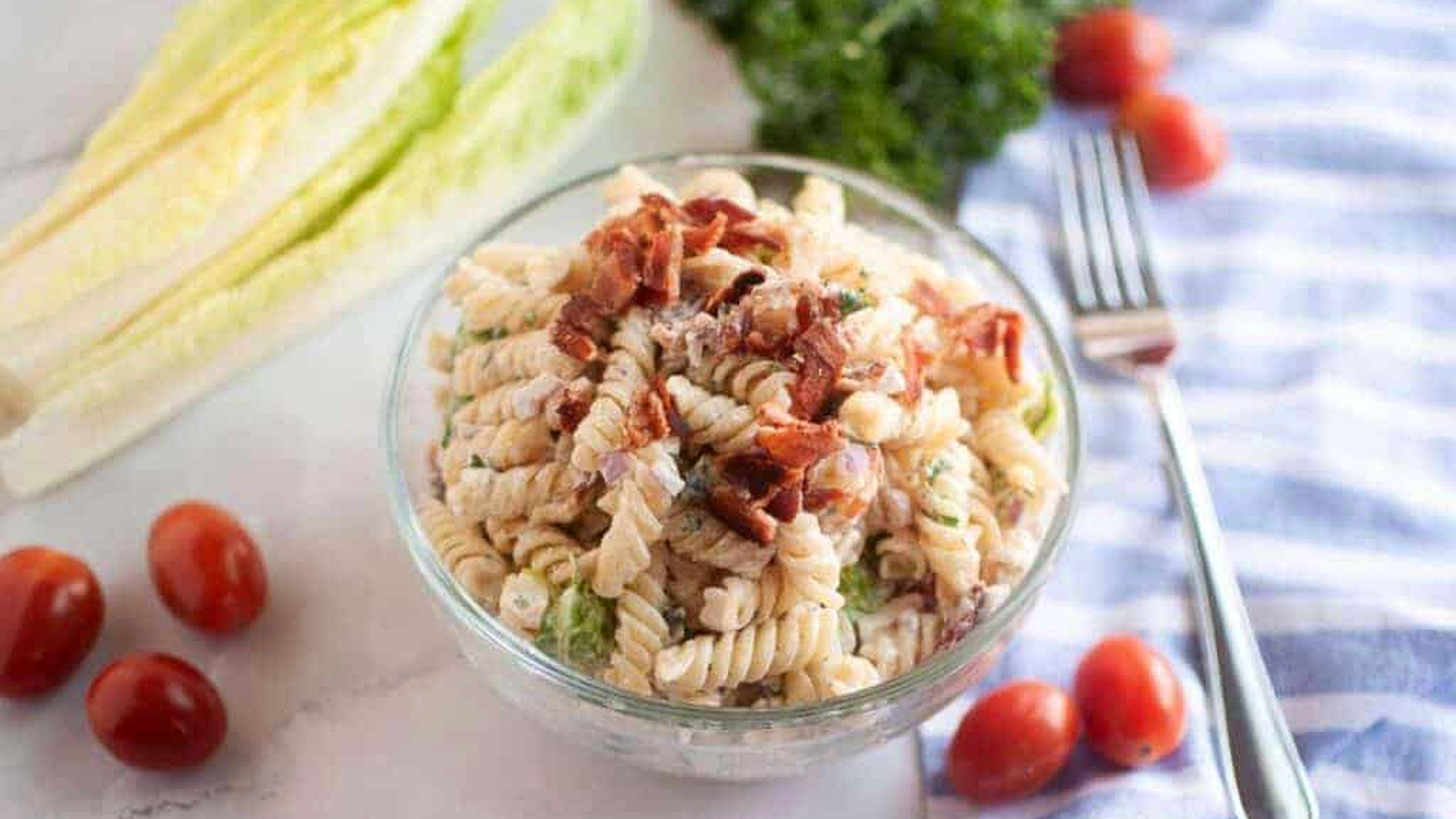 Overhead shot of a glass bowl filled with BLT pasta salad.