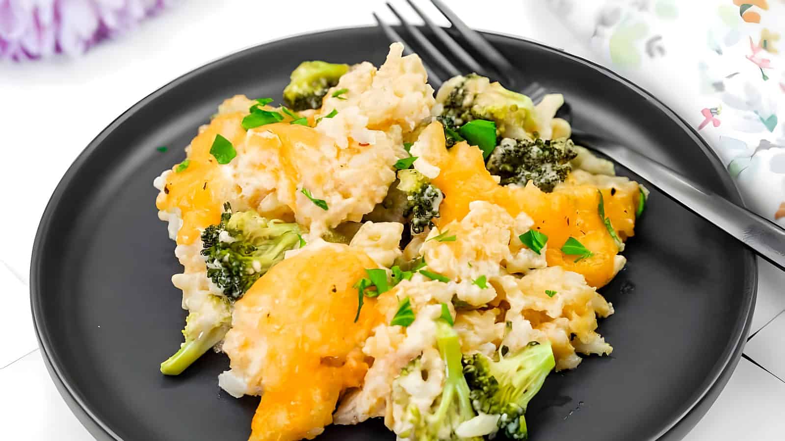 A serving of Broccoli Rice Casserole with Fresh Broccoli on a black plate.