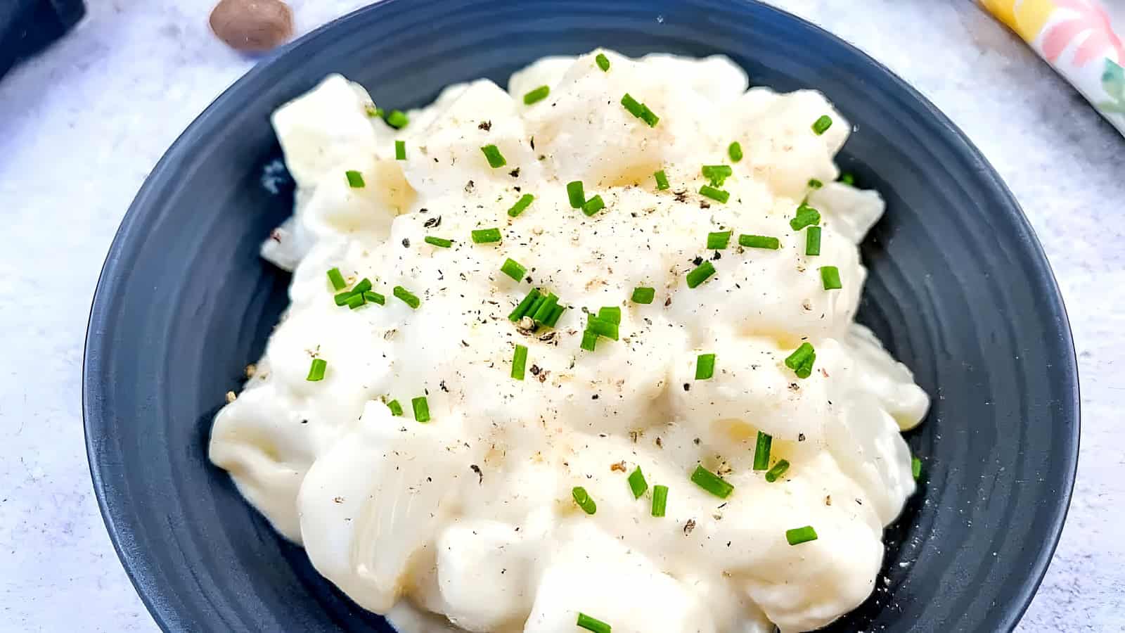 German Kohlrabi in Cream Sauce on a black plate.