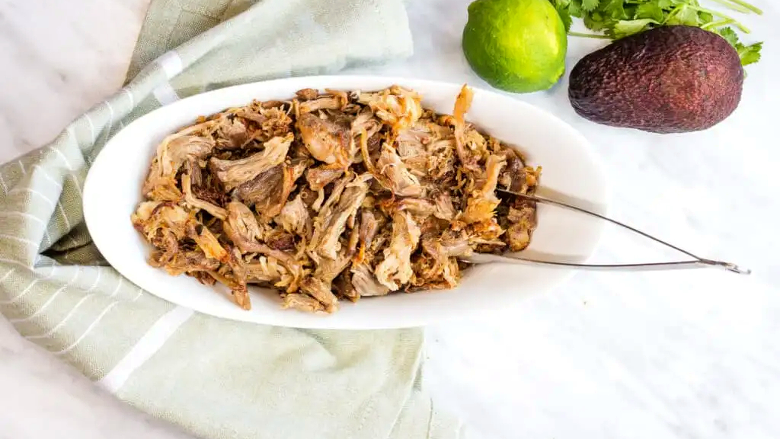 Al Pastor Carnitas in a white bowl with tongs.