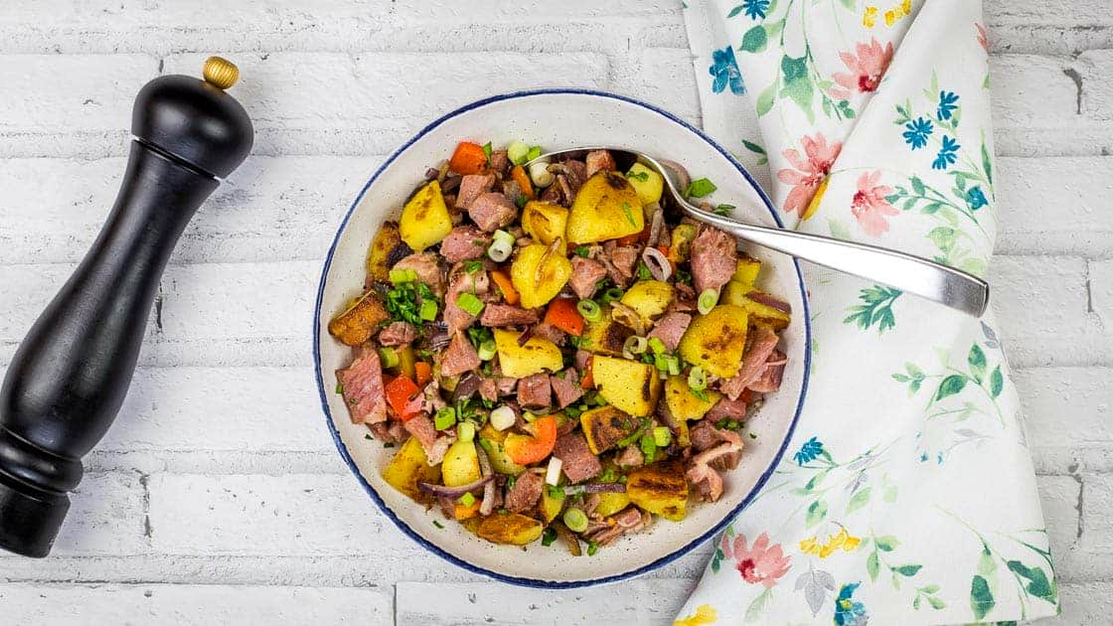 A bowl of leftover cottage roll hash on a white tablecloth.