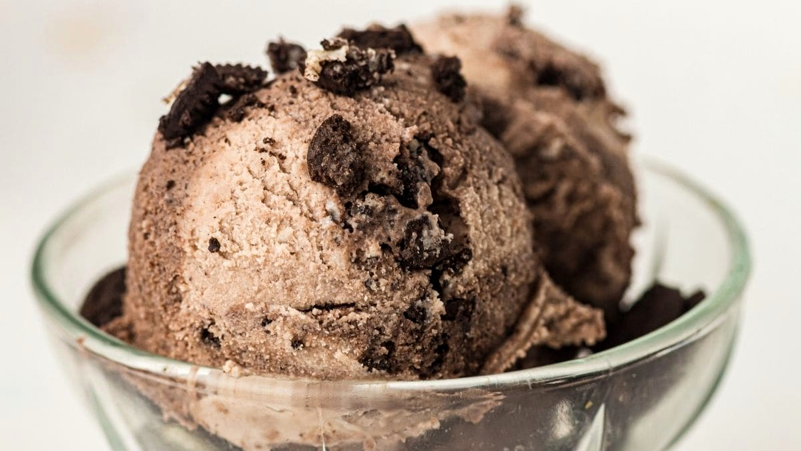 Two scoops of Cookies And Cream Ninja Creami Ice Cream in a clear glass bowl.