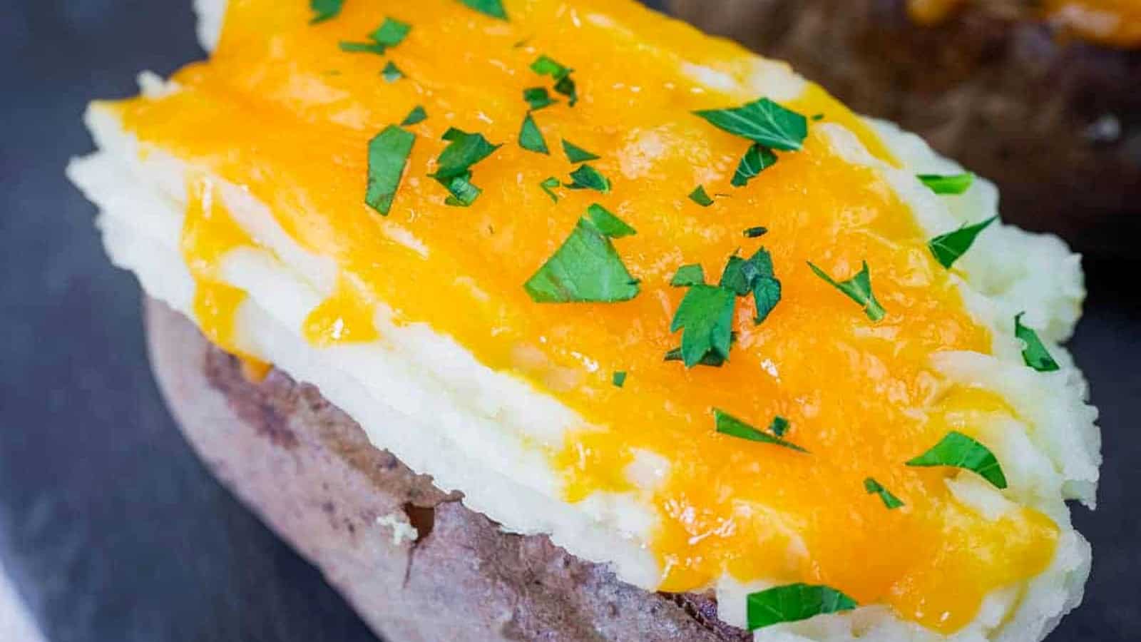 Close-up of Shepherd&rsquo;s Pie Baked Potatoes topped with melted cheddar cheese and chopped parsley.