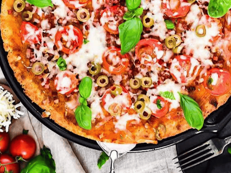 Keto Bacon Fathead Pizza with fresh basil leaves.