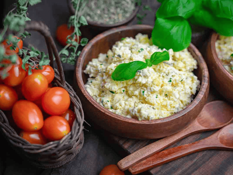 Bowl of creamy feta eggs garnished with basil.