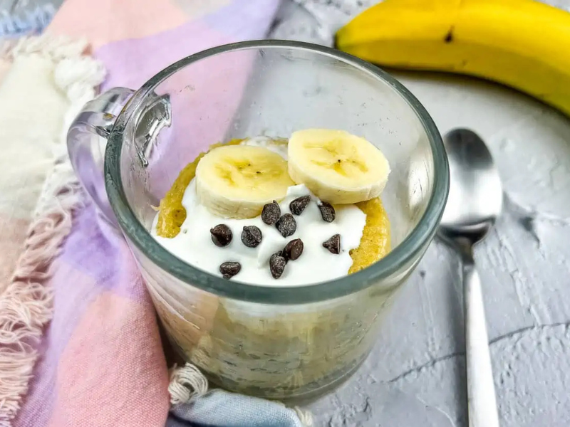 Banana chocolate mug cake with spoon and banana.