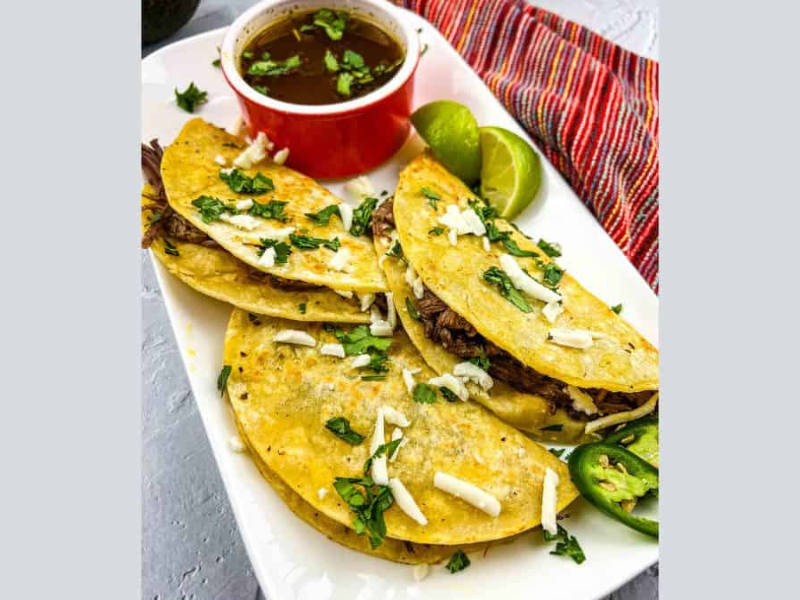 Birria Tacos on a plate with consomme.