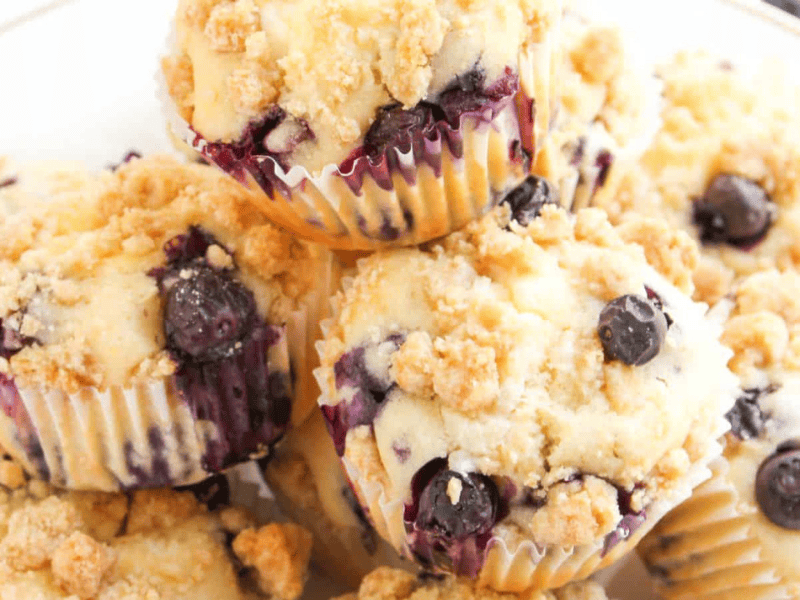 A plate of blueberry muffins with crumb topping, arranged in a pile.