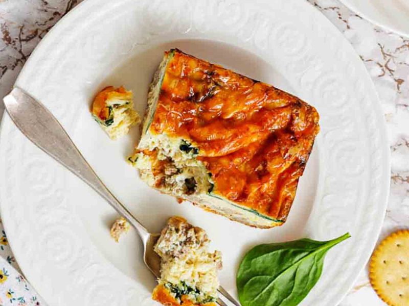 Sausage egg strata slice on white plate.