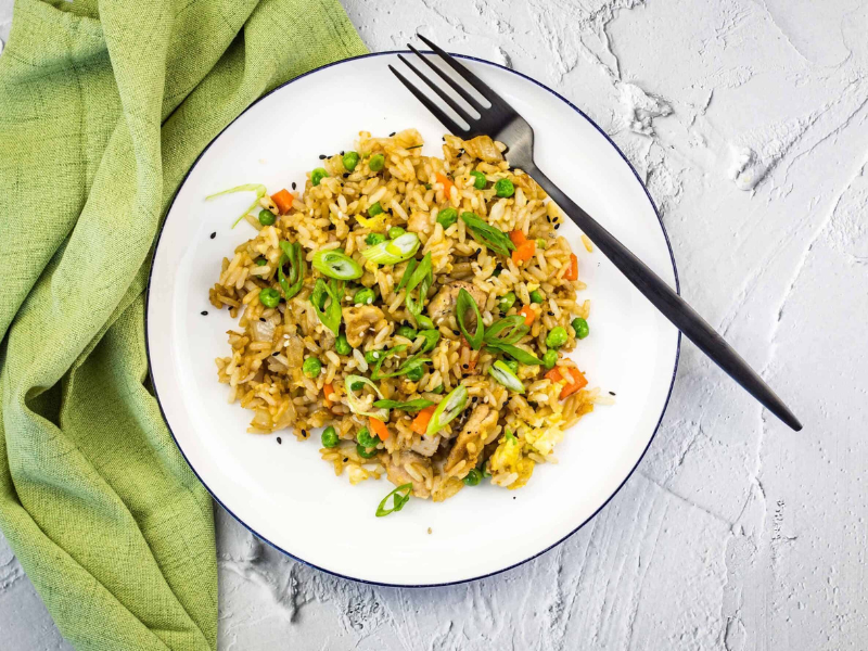 Chicken fried rice on a white plate with a green napkin.