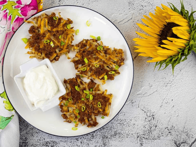 Corned beef fritters and a dip on a white plate with a sunflower on side.