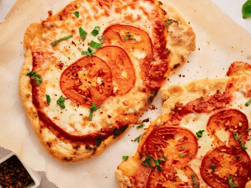 Two slices of pizza with tomatoes and herbs.