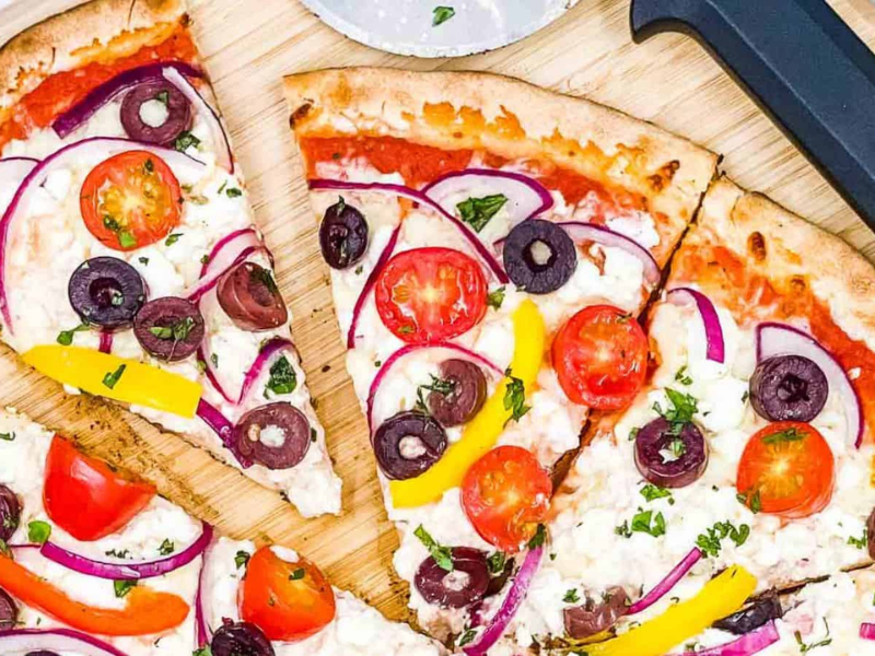 Greek pizza, sliced on a board.