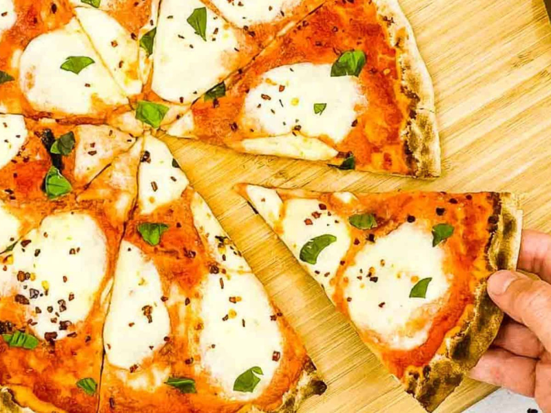 Someone helping themselves to a slice of Margherita pizza.