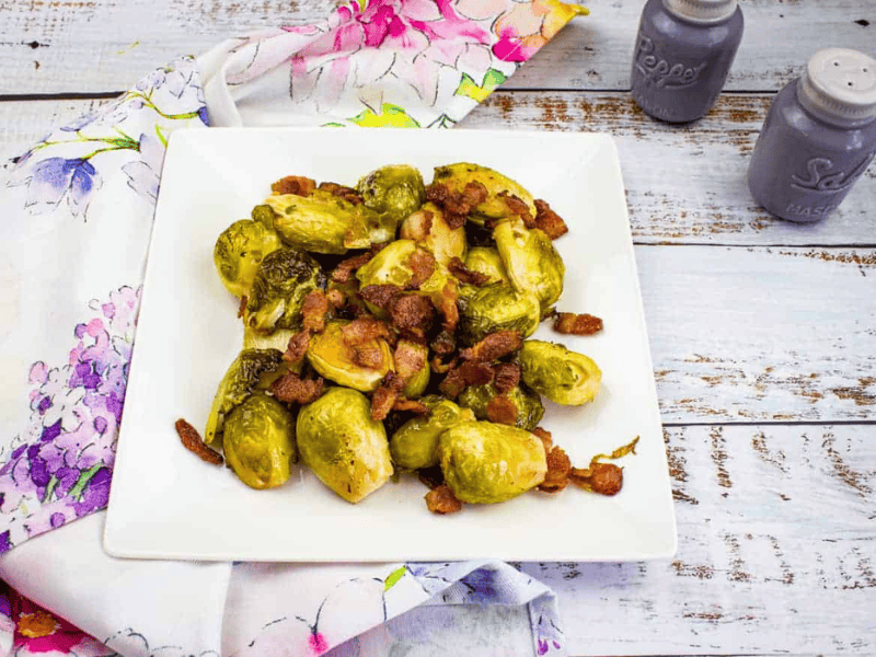 Smoked Brussels Sprouts with bacon on a white plate.