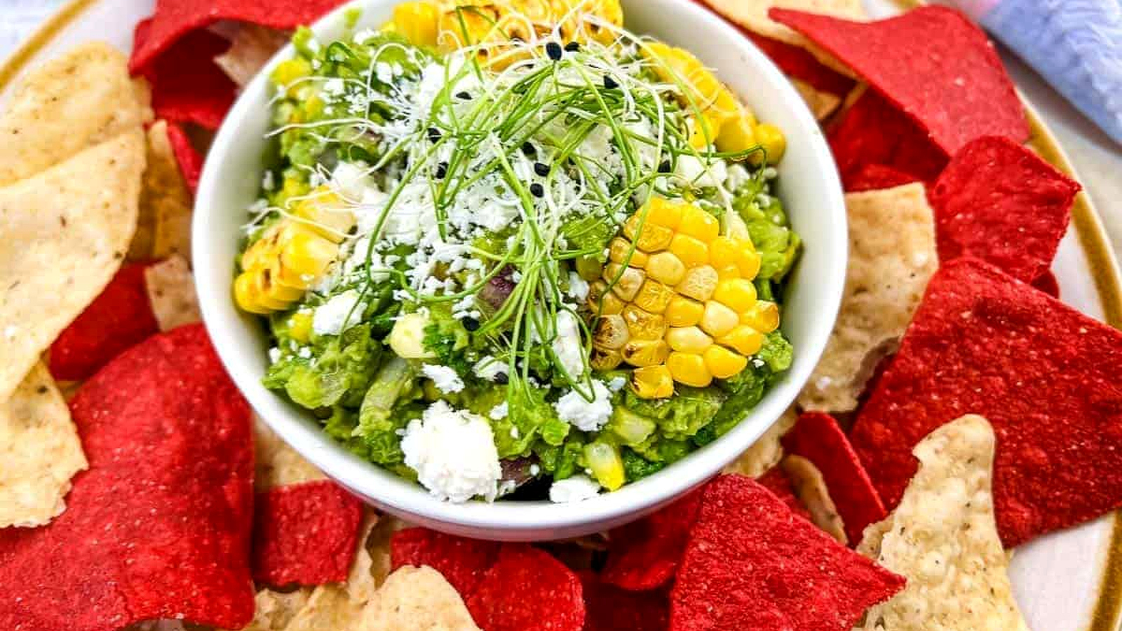 Corn guacamole with tortilla chips on a plate.