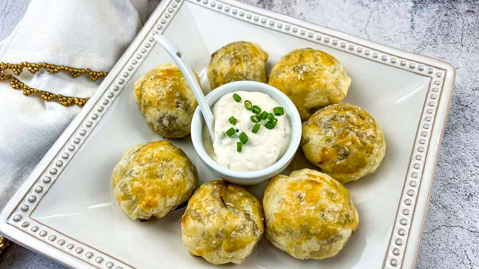 Beef Wellington Bites on a white plate with sauce in the middle.