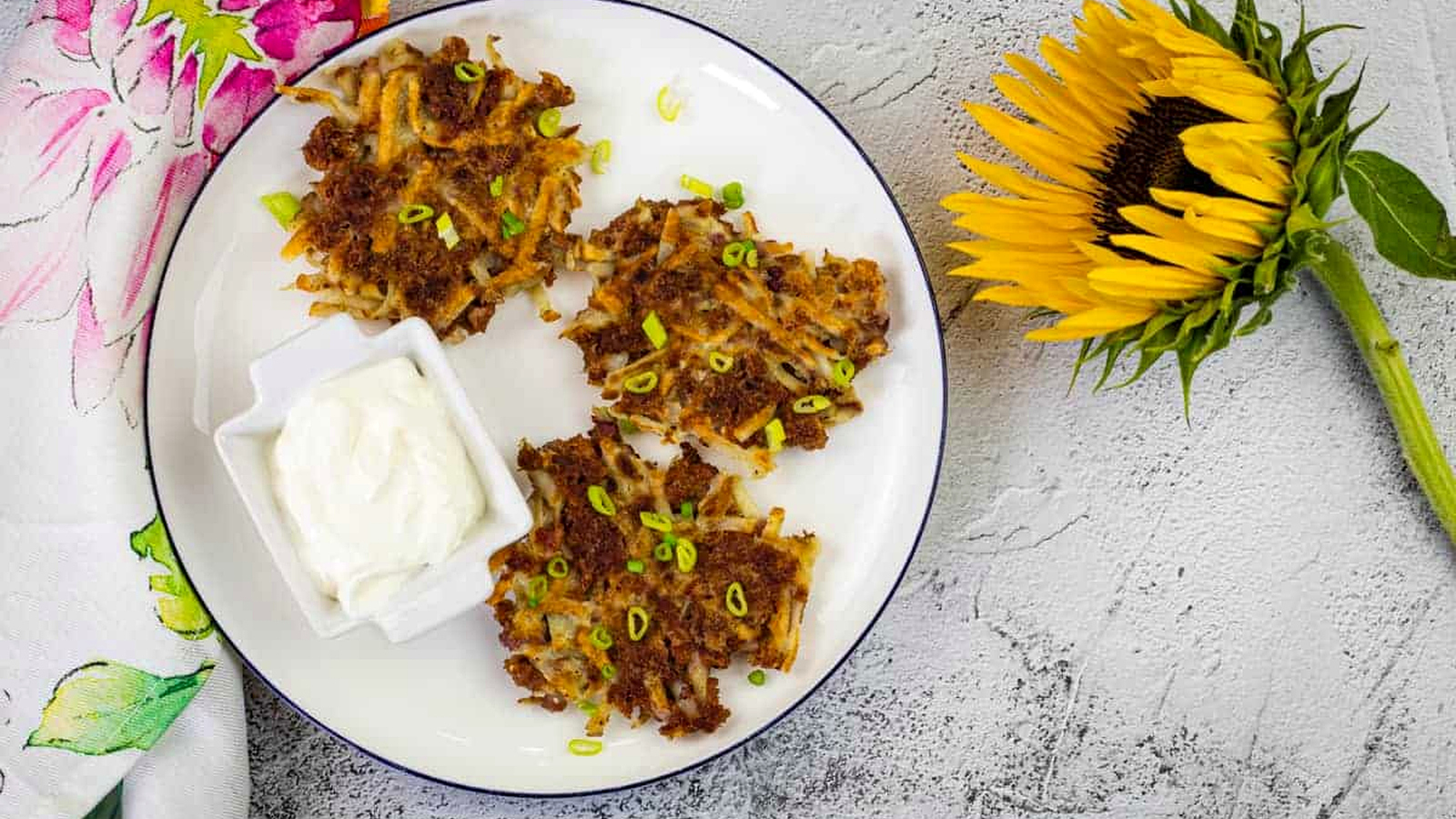 Corned beef fritters and a dip on a white plate with a sunflower on side.