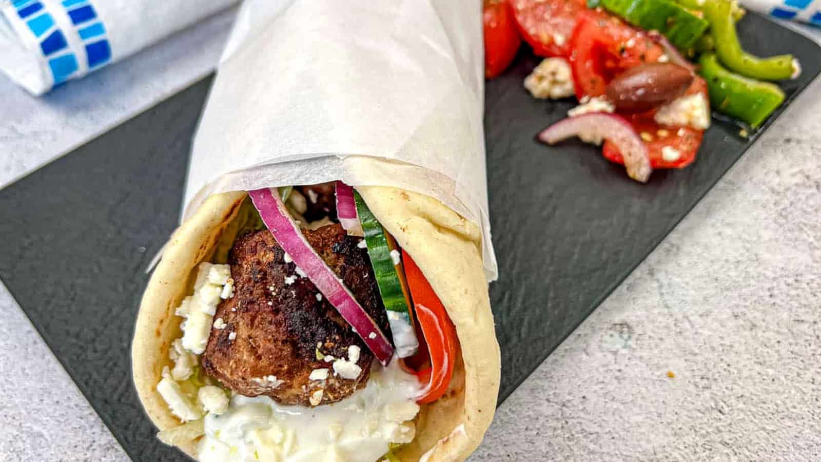 Greek Meatball Pita Sandwich served on a black slate plate.