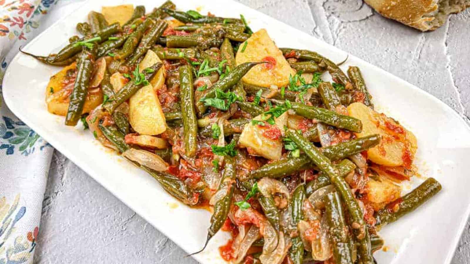 Greek Green Beans served on a white rectangular plate.