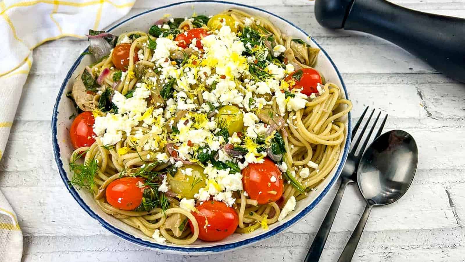 A bowl of pasta with tomatoes, feta and kalamata olives.