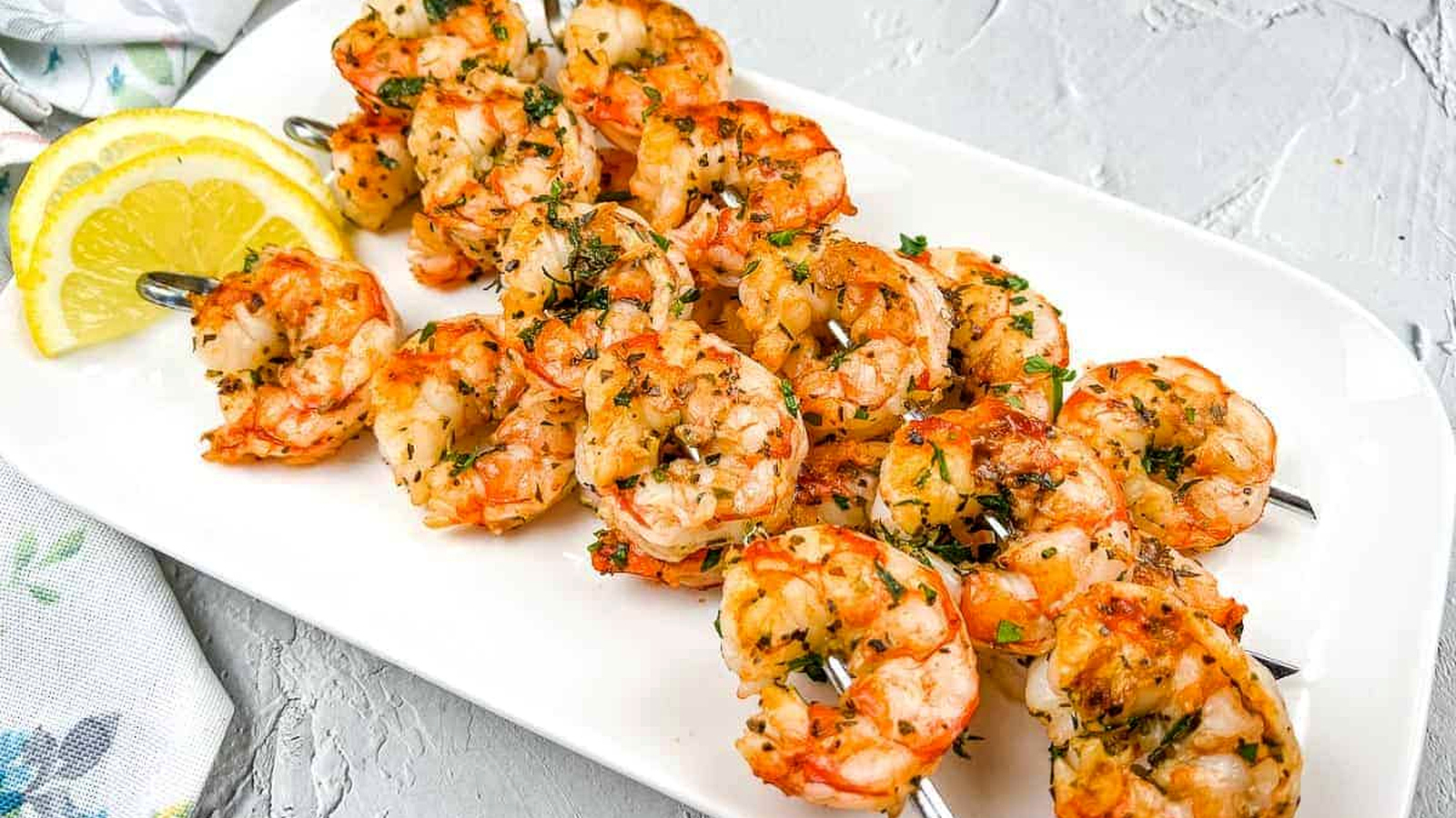 Mediterranean Grilled Shrimps on a white plate with lemon wedges.